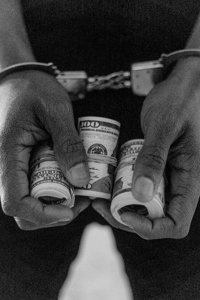 person in handcuff holding rolled dollar bills